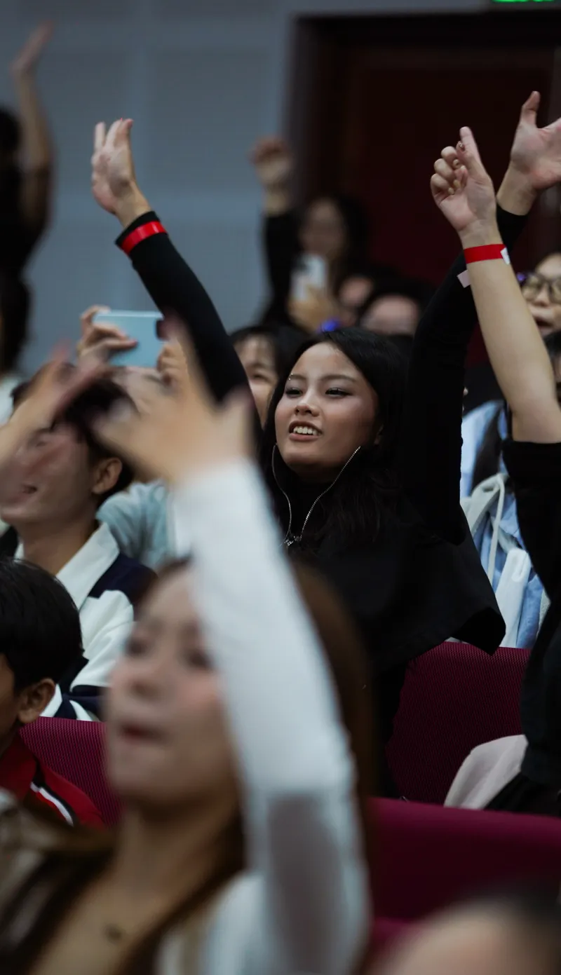 Student audience cheering with arms raised during the gala night