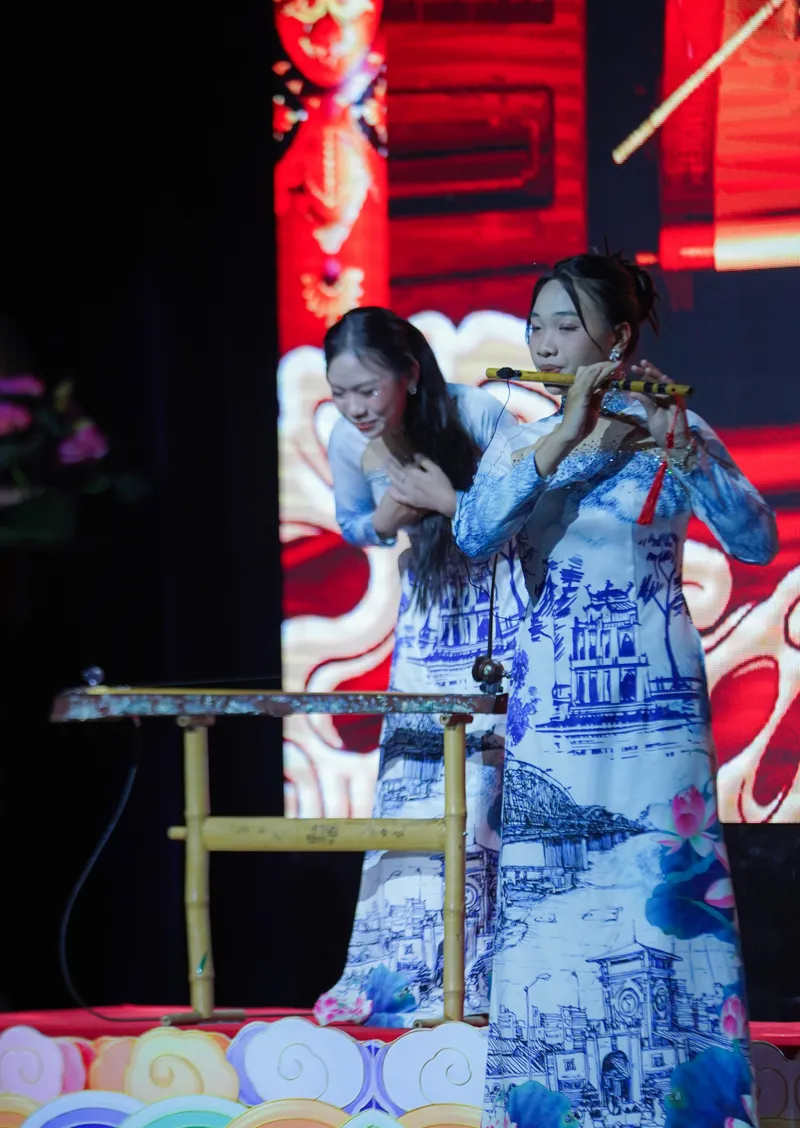 Musicians in blue-and-white áo dài performing with bamboo flute and traditional zither