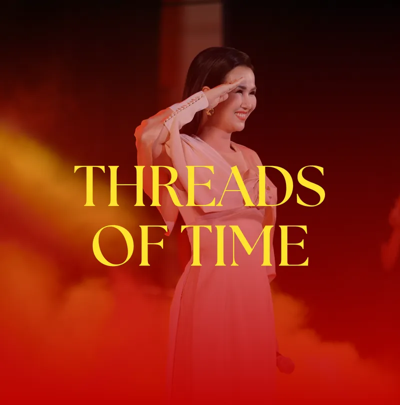 Threads of Time — performer in a pale áo dài saluting amid red-lit haze