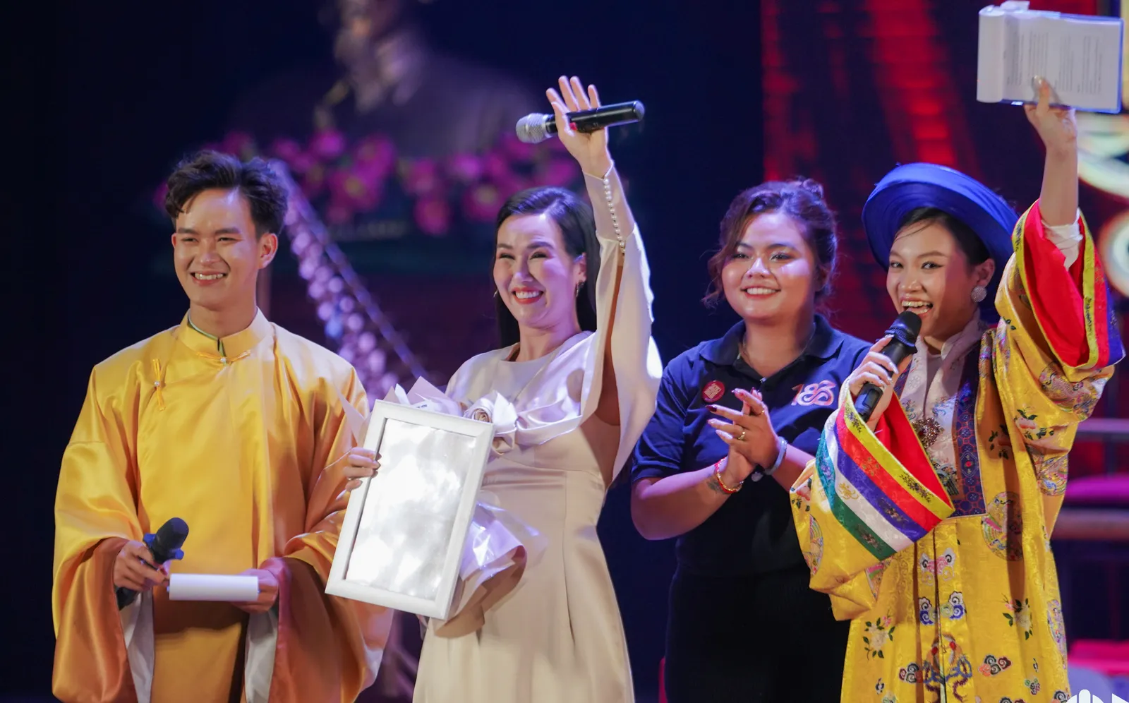 Sponsor recognition on stage — guests receive a certificate and flowers beside MCs in traditional attire