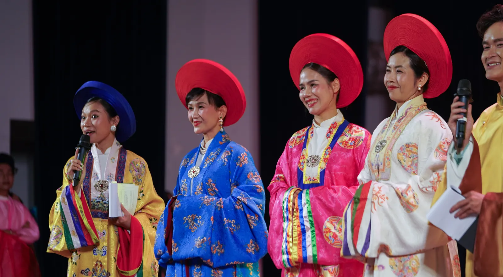 Models in colorful Nhật Bình robes and flat circular hats presented on stage